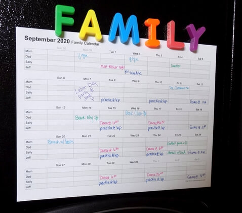Monthly family calendar print out with hand-written schedule and posted on a refrigerator